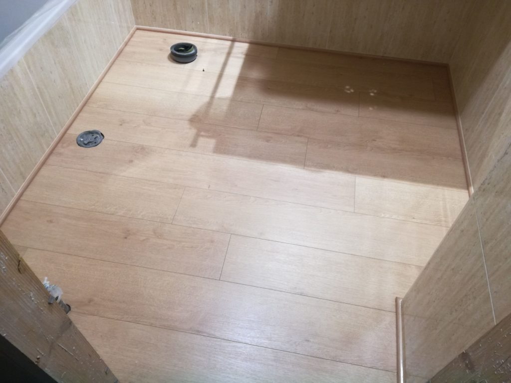 Suelo de tarima laminada Aqua Plus instalado en un cuarto de baño, resistente al agua y con un acabado elegante.